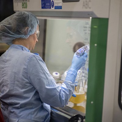 A woman wearing protective clothing using equipment in a science laboratory